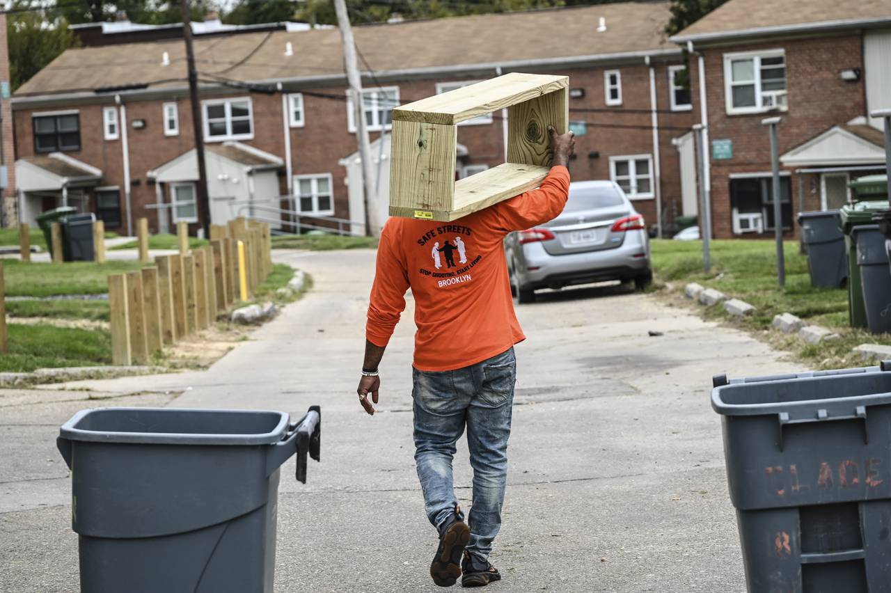 A member of Baltimore Safe Streets carries a new flower bed to a home in Brooklyn during the Healing Day event on Saturday
