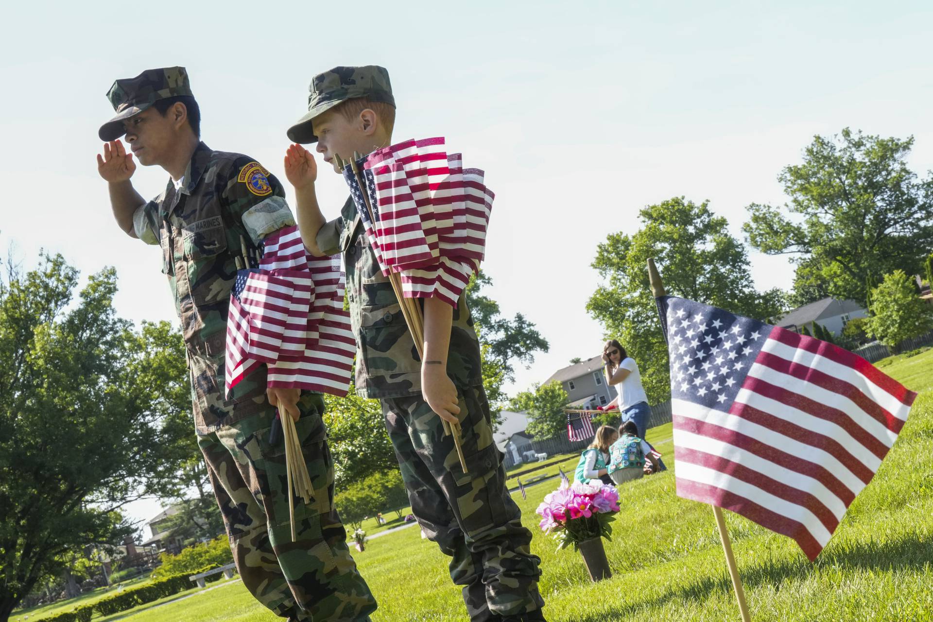 Young Marine Gunnery Sergeant Colin Farias, 16, and Private Duffy, 8, plant flags on gravesites at Dulaney Valley Memorial Gardens on May 27, 2023.