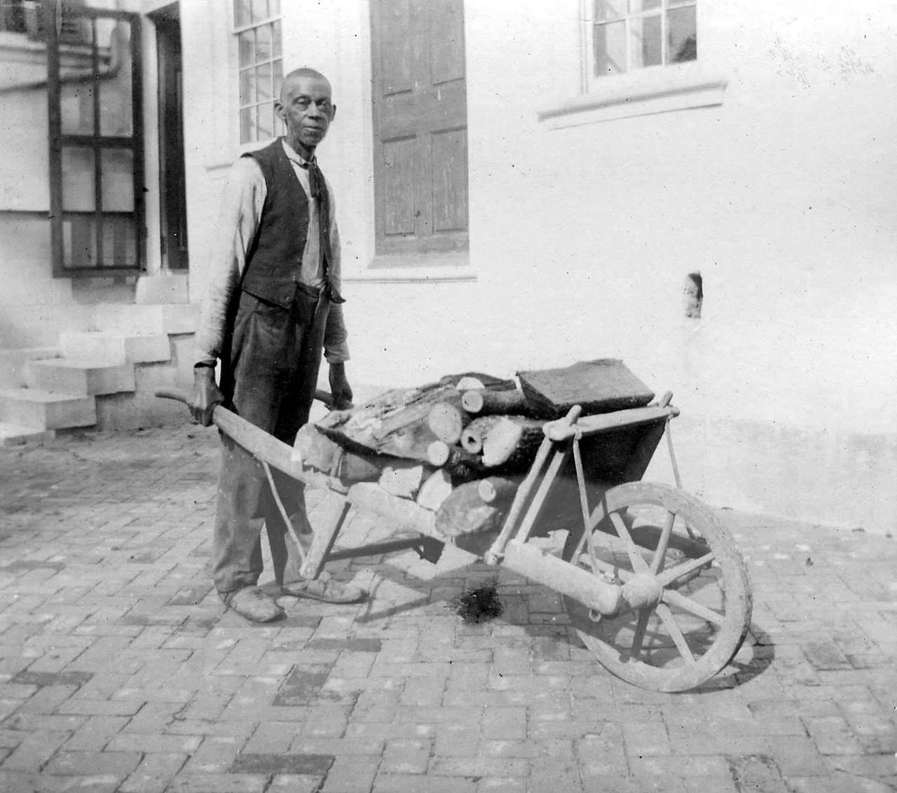 Jim Pratt, a formerly enslaved farm worker, with wheelbarrow in front of the south facade of the Hampton mansion, 1895.