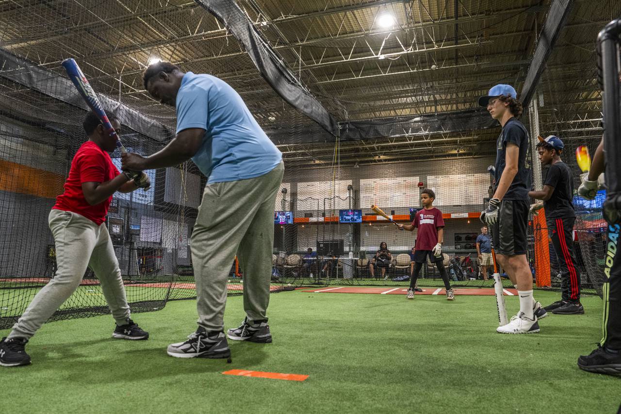 Coach Kellen Wallace helps children with their form and batting skills. Children learn baseball skills at the Baltimore Urban Baseball Academy, BUBA, in South Baltimore on October 4, 2023.