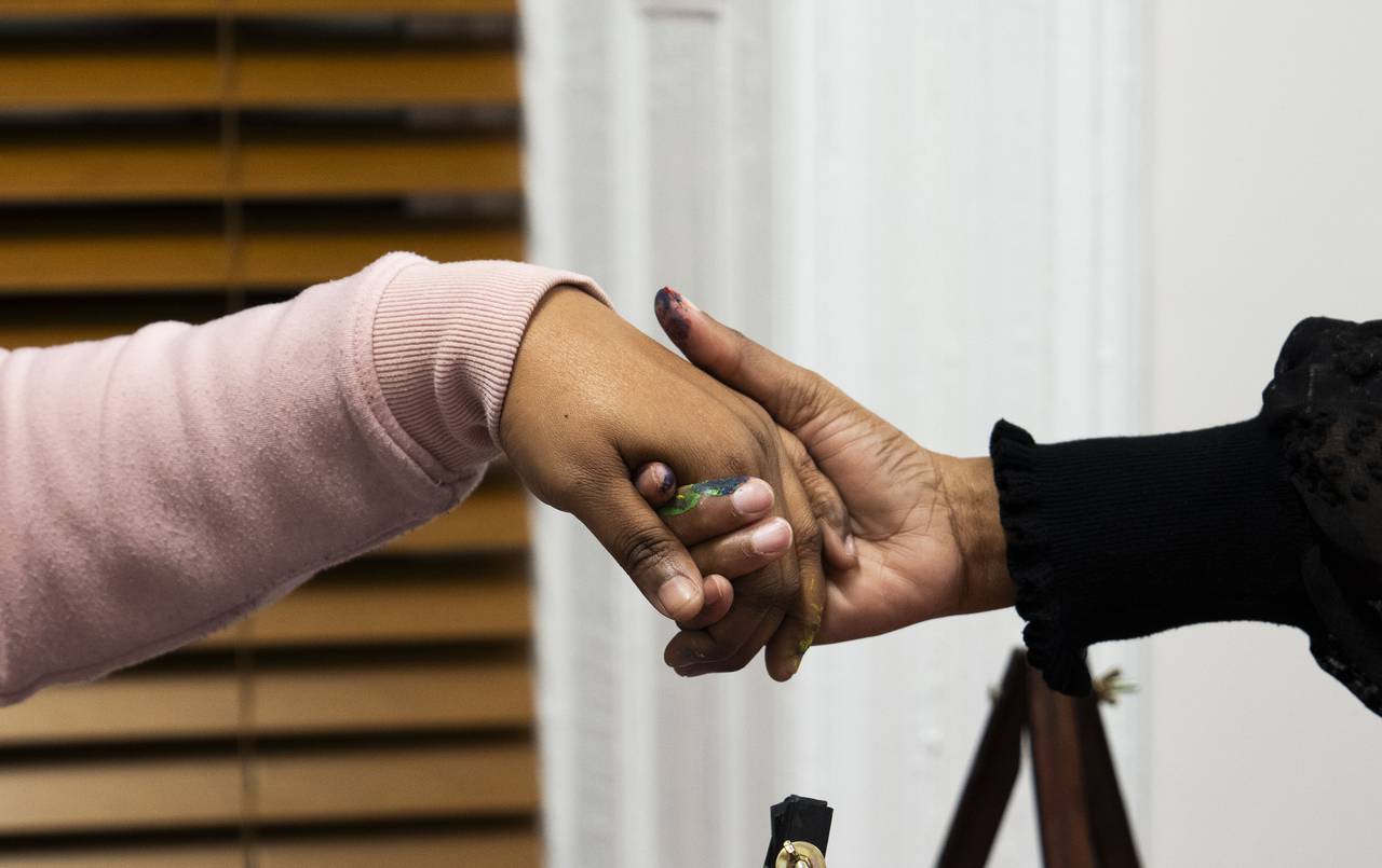 Tameka Lynbrith, mother of Kylis Fagbemi, who was killed in the Brooklyn Homes shooting in July, holds hands during prayer with Donna Bruce at Sip and Paint night on December 16, 2023.
