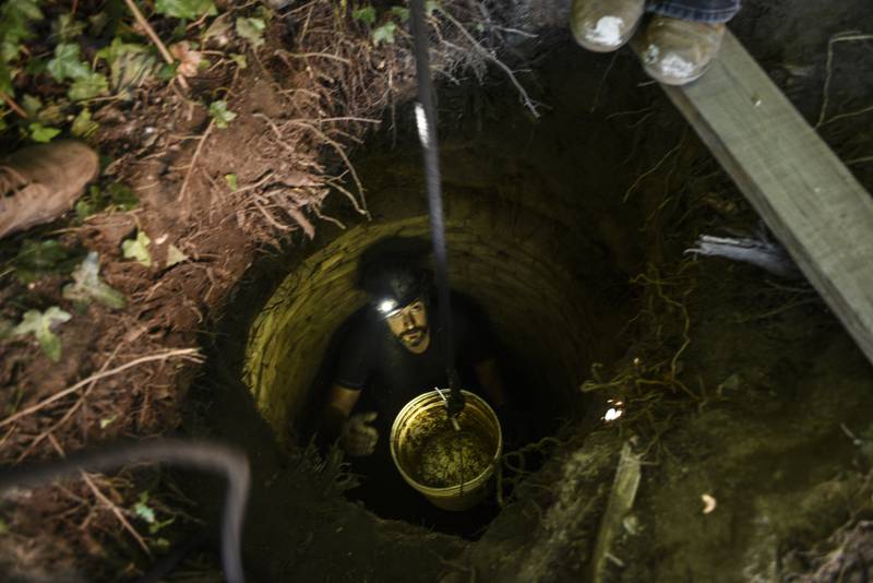 Matt Palmer takes an empty bucket down in a privy hole to fill it with dirt.