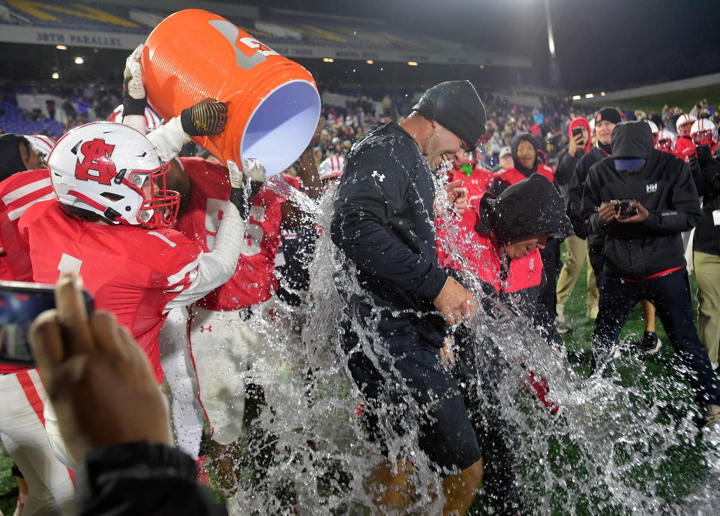 Archbishop SpaldingÕs PJ Poknis, #1, and Dillon Jones, #55, pour water on head coach Kyle Schmitt after the team beat Calvert Hall 34-10 in the MIAA A Conference football championship, Friday, Nov. 18, 2022 at Navy-Marine Corps Memorial Stadium in Annapolis.