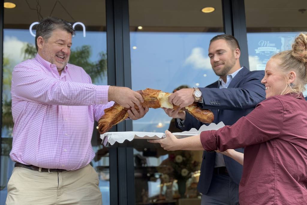 Neman Popov, the founder of Roggenart European Bakery, Bistro and Cafe, left, splits a very large croissant with owner and partner Brody Tennant outside the City House Charles office complex.
