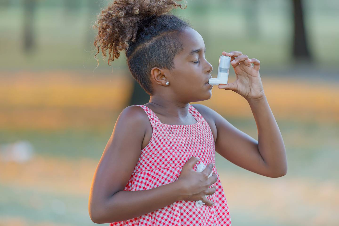 Cute Little Girl with Curly Hair is Walking in Public Park and Using an Asthma Inhaler Due to the Problems with Breathing.