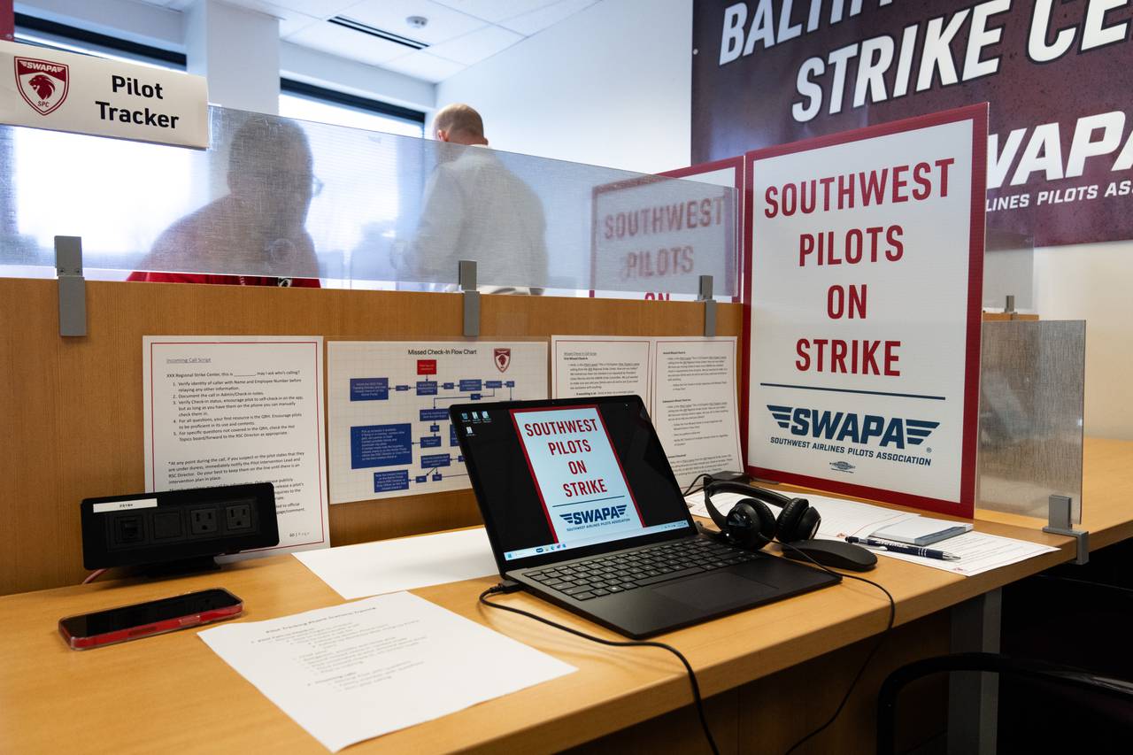 A pilot tracker station has a laptop, a sign reading "Southwest pilots on strike," and papers explaining how to do pilot tracking on it.