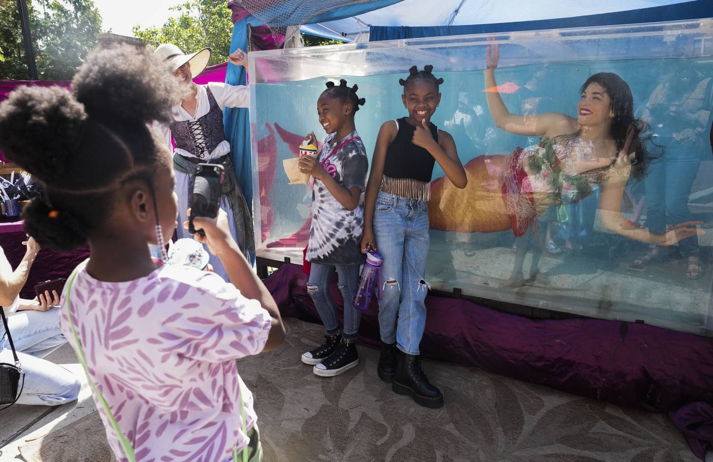 Laila Riley, 10, and Laci Riley, 7,  gather to see the "mermaid" at the Rotunda, courtesy of Circus Siren Pod, before the premiere of the Little Mermaid movie on May 27, 2023.