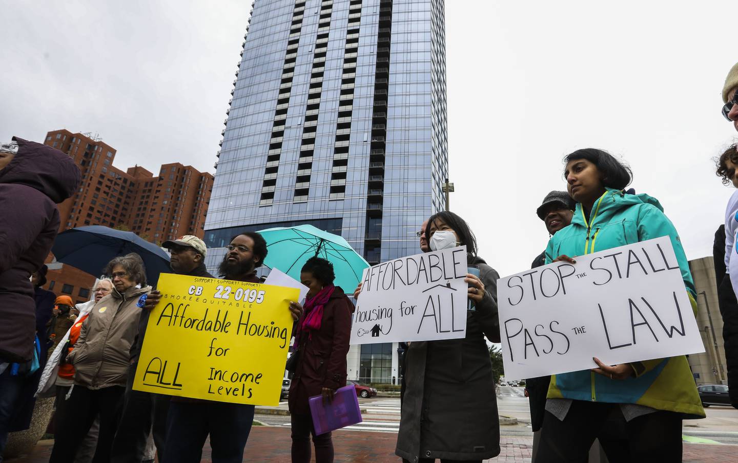 Terrel Askew, 35, Hieu Truong, 38, and Loraine Arikat, 26, all from Baltimore hold up signs in support of affordable housing. A rally in support of the BMOREEquitable Council Bill 22-0195, which demands equitable and affordable housing options for all, took place outside of 401 Light Street on October 3, 2022.