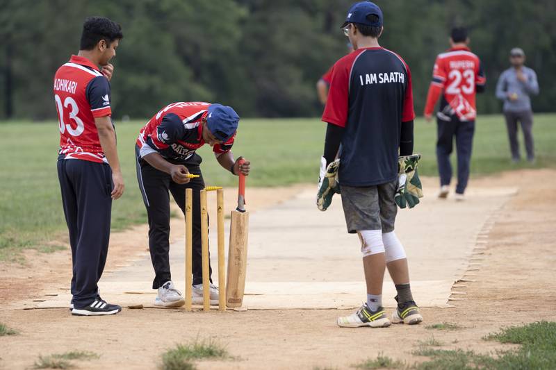 A cricket player delicately places a bail on the stumps during practice July 27.