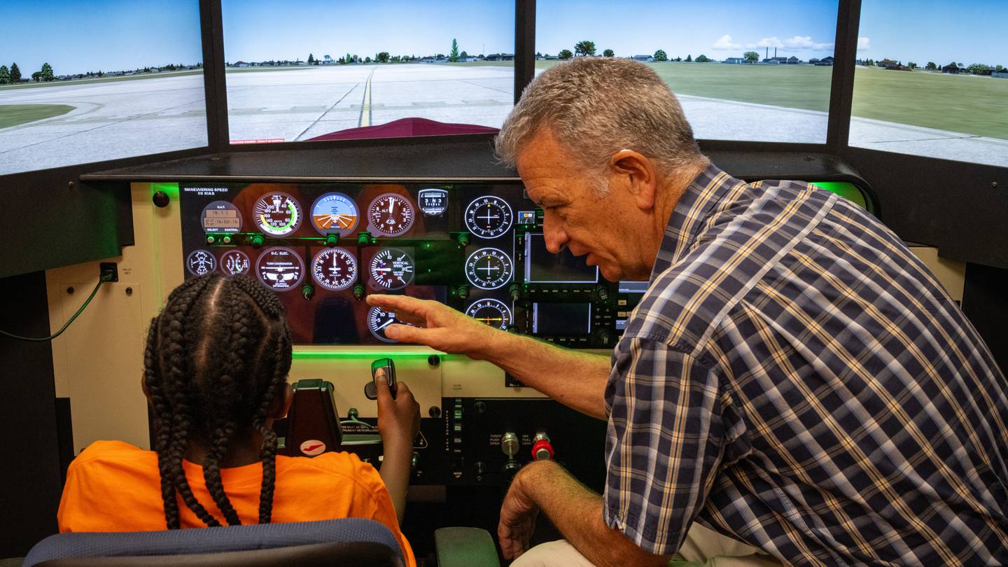 Instructor Jerry Hinshaw teaches a camper how to take off from the runway during a flight simulation.