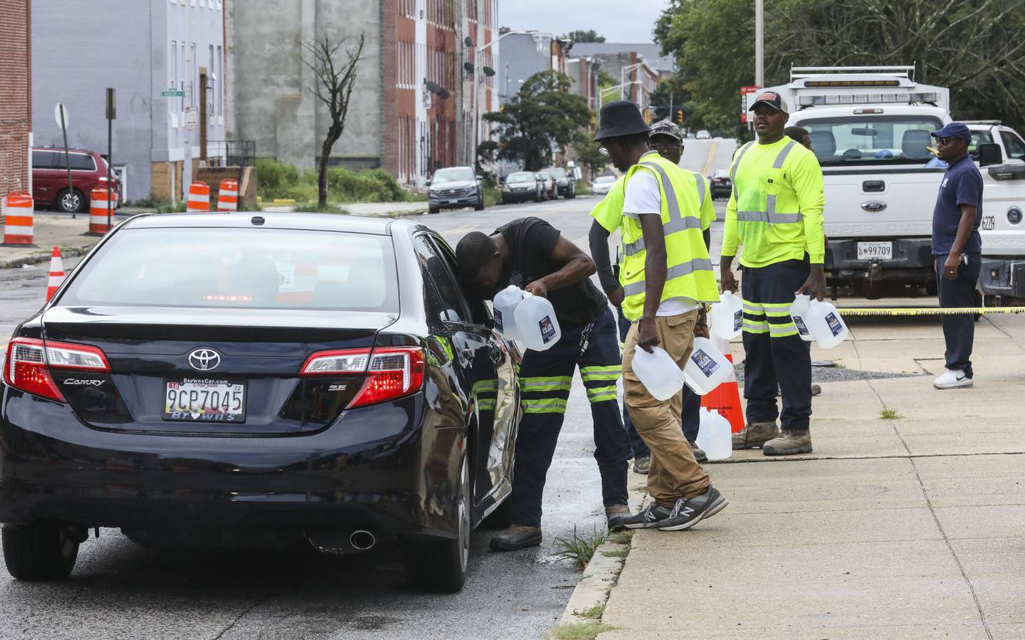 Baltimore Department of Public Works employees hand out water in Harlem Park after the city issued a boil advisory. Baltimore’s public works department first noted E. coli and coliform through routine testing on Friday.