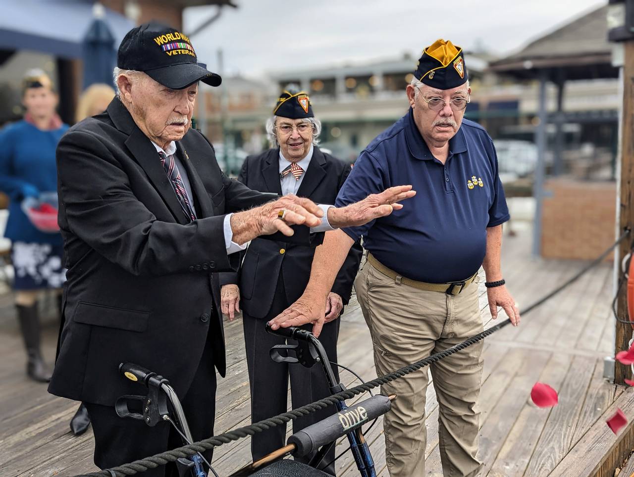 Iron McAfee Locklear, 97, of Glen Burnie tosses rose petals into the water Thursday during a remembrance of the attack on Pearl Harbor. He was helped by club members Claire Purdy and Tom Webb.