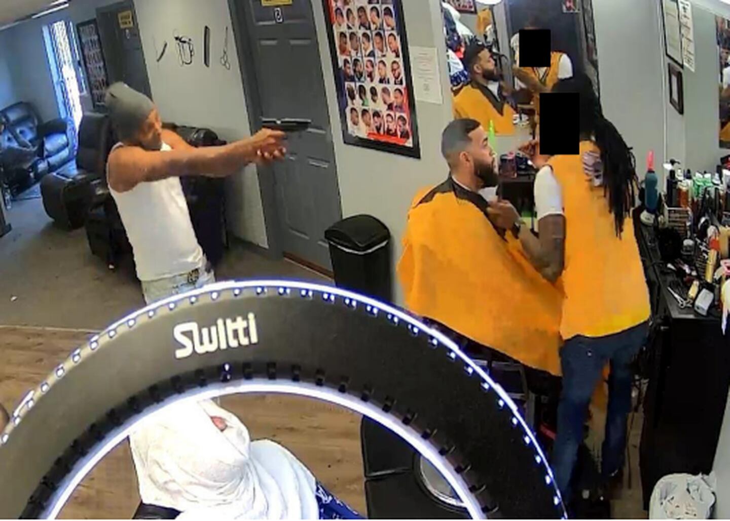 A still from surveillance camera footage shows the moment Carlos Ortega, left, shot Rafael Jeffers, right, while David Burch, an off-duty Baltimore Police Department sergeant, sat in Jeffers' barber's chair.