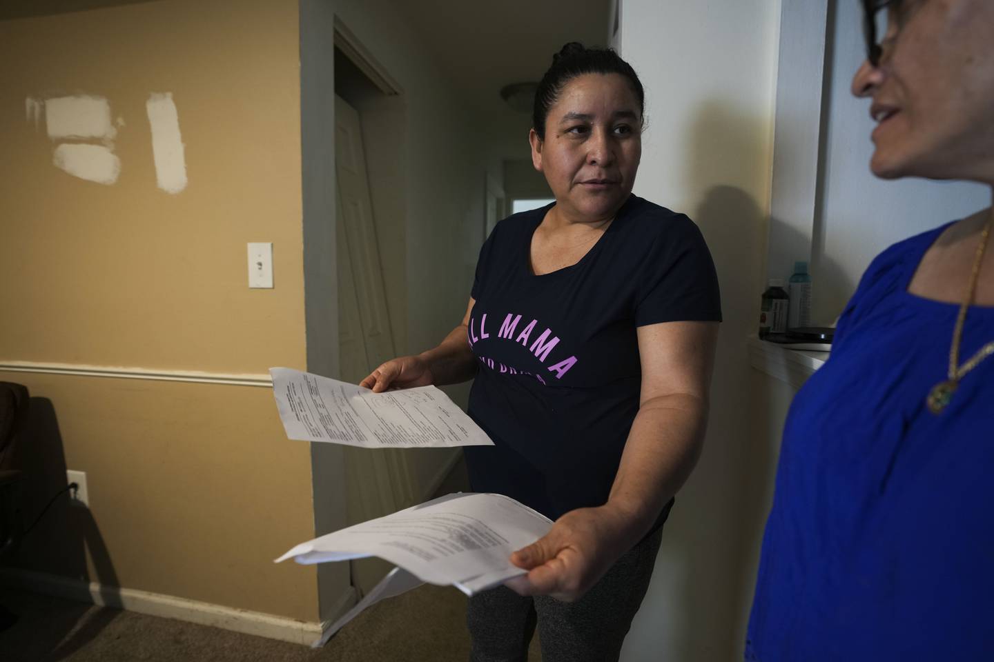 Verónica del Cid Gaitán, an undocumented immigrant, shows paperwork from a recent surgery to Viviana Lozano and CASA lead organizer. Gaitán has had one recent follow-up appointment with another scheduled in June and has no insurance to cover them. She is pictured here in her home on April 14, 2023.