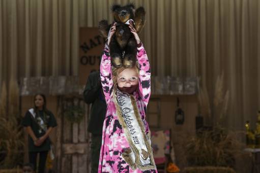 Little Miss Outdoors 2023 holds up a teddy bear made of muskrats during the live auction. The bear fetched $2,000.