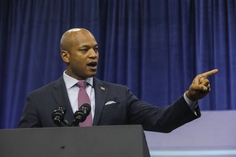 Wes Moore stands behind a lectern speaking, his left arm extending and pointing a finger for emphasis.