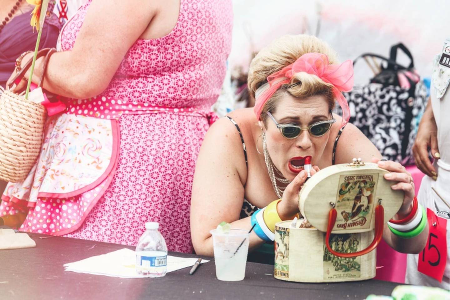 A woman puts on lipstick to complete her look as a Baltimore "hon" at HONFest in 2018.