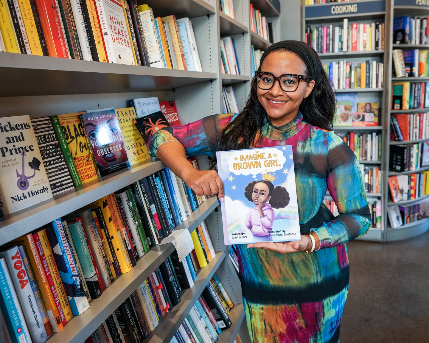 Inside of the bookstore, Bird in Hand, Sheri Booker takes a portrait holding her new children's book, in Charles Village, Md., on November 19, 2022. Booker teaches multiplatfrom production at Morgan State University.