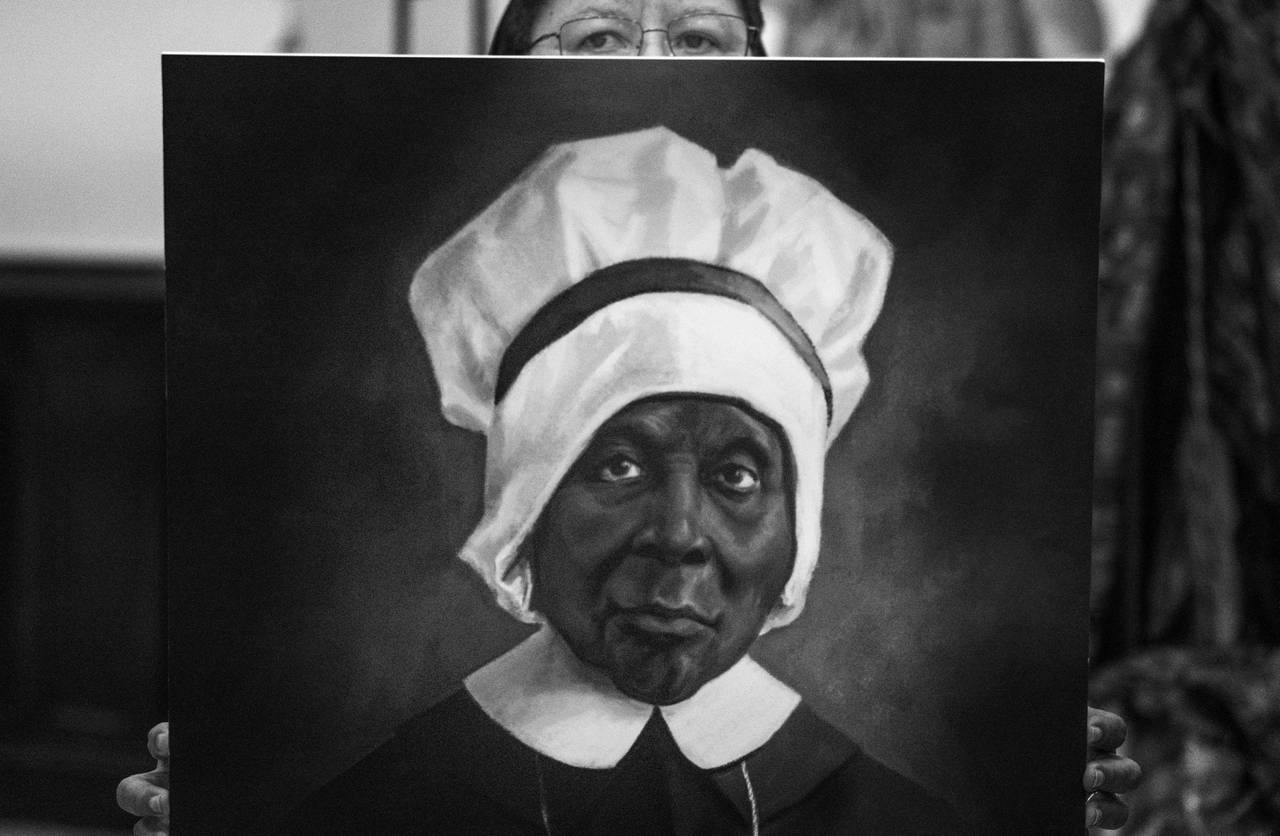 Sister Rita Michelle Proctor carries a portrait of Mother Mary Lange during All Saints Day Mass at St Francis Xavier Catholic Church, Tuesday, November 1, 2022. Mass was held to expedite the canonizations of the first six African American candidates for sainthood.