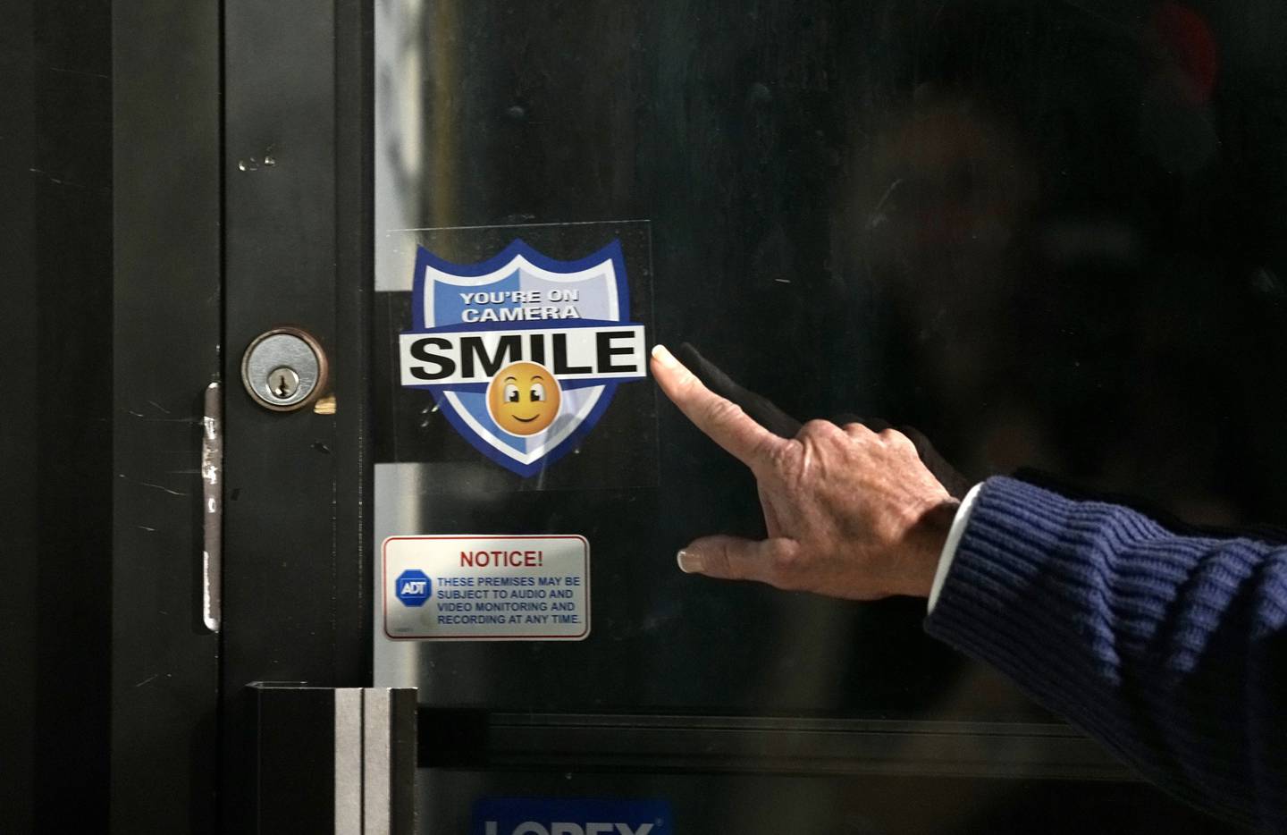 Towson Chamber of Commerce Executive Director Nancy Hafford points at a security sticker on a business door during a public safety walk down York Road and Allegheny Avenue, visiting businesses along the way on February 22, 2023.
