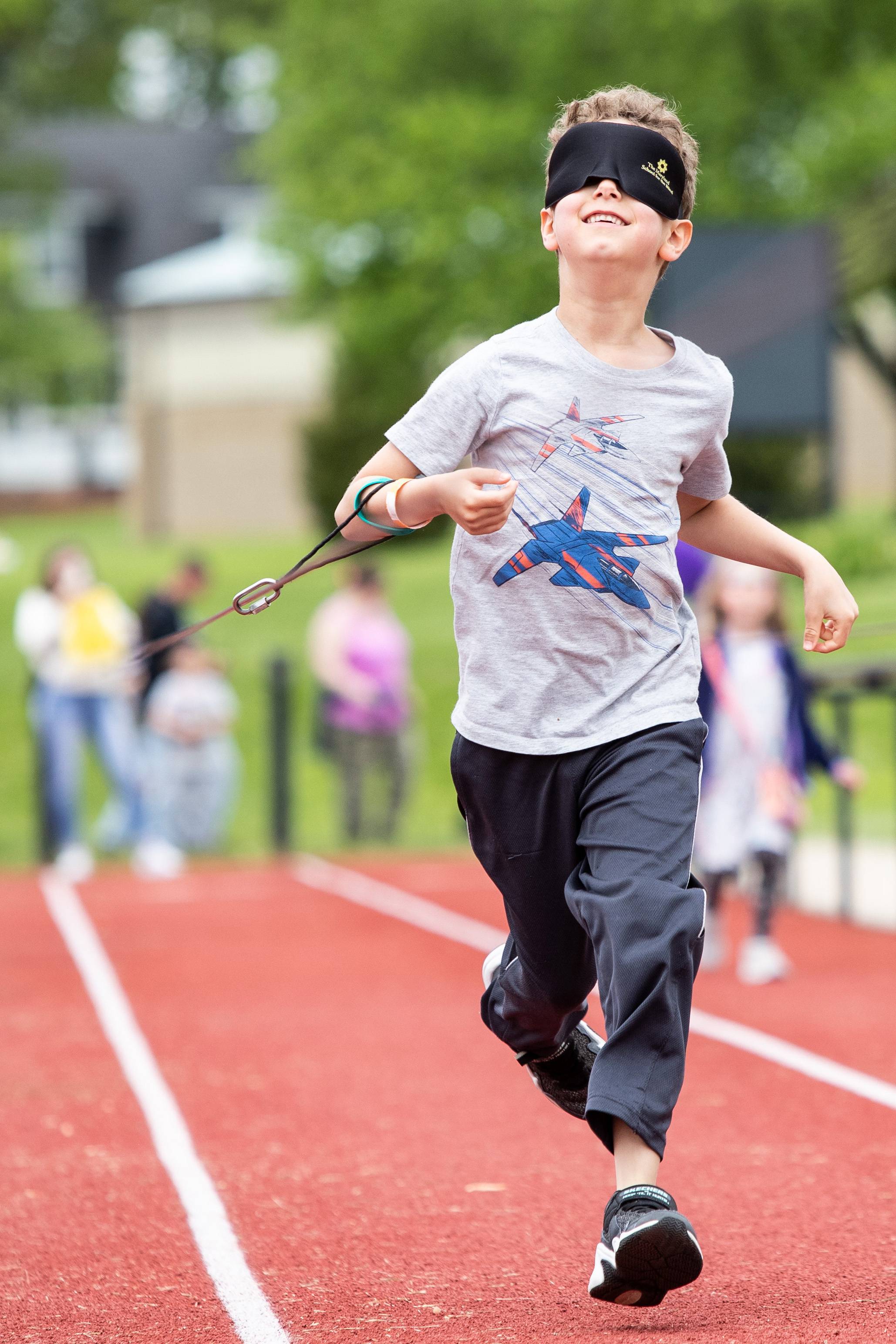 A young boy runs on The Maryland School for the Blind sprint track, with eyeshades, at the See Beyond festival.