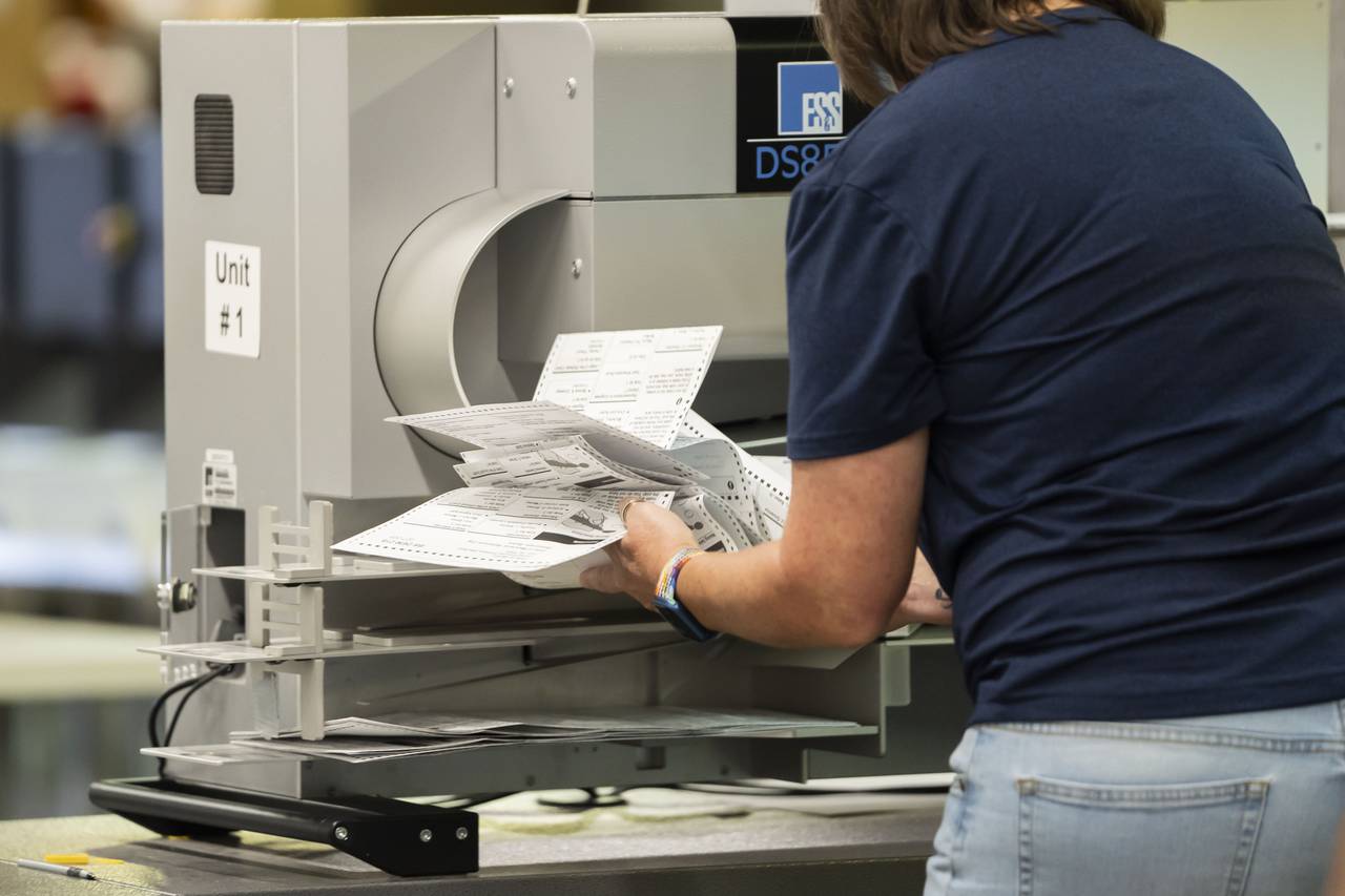 A ballot counter runs mailed-in ballots through a machine and gathers them if they get stuck.