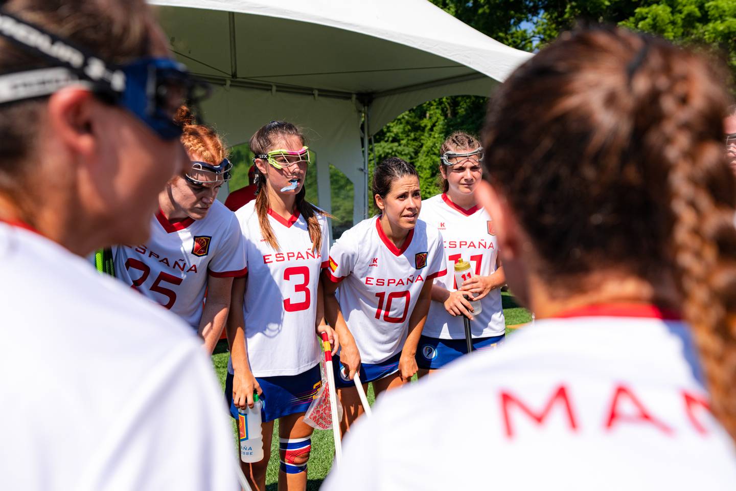 Carmen Navas-Migueloa, center, huddles with the Spanish Women's National Lacrosse team.