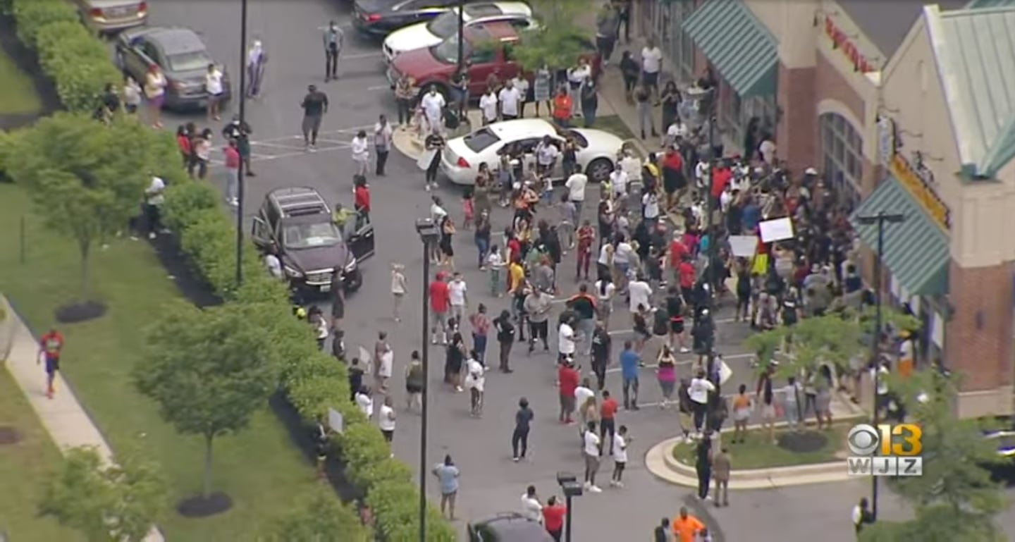 A still image from aerial footage shows dozens of people protesting in June 2020 outside a strip mall where Vince's Crab House is located. They are demonstrating against racist posts published on social media by the restaurant's operator.