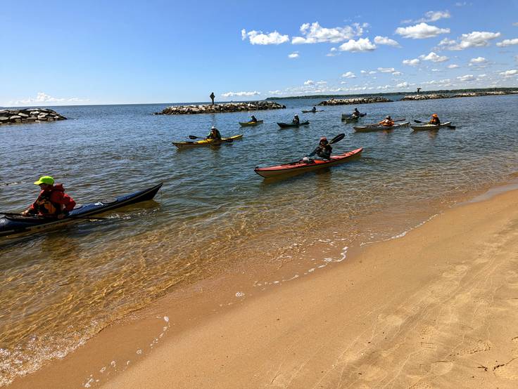 Kayakers paddle along the golden sand beach at Beverly Triton Nature Park just before a dedication ceremony on Friday, May 5. The beach will open for swimming this summer.