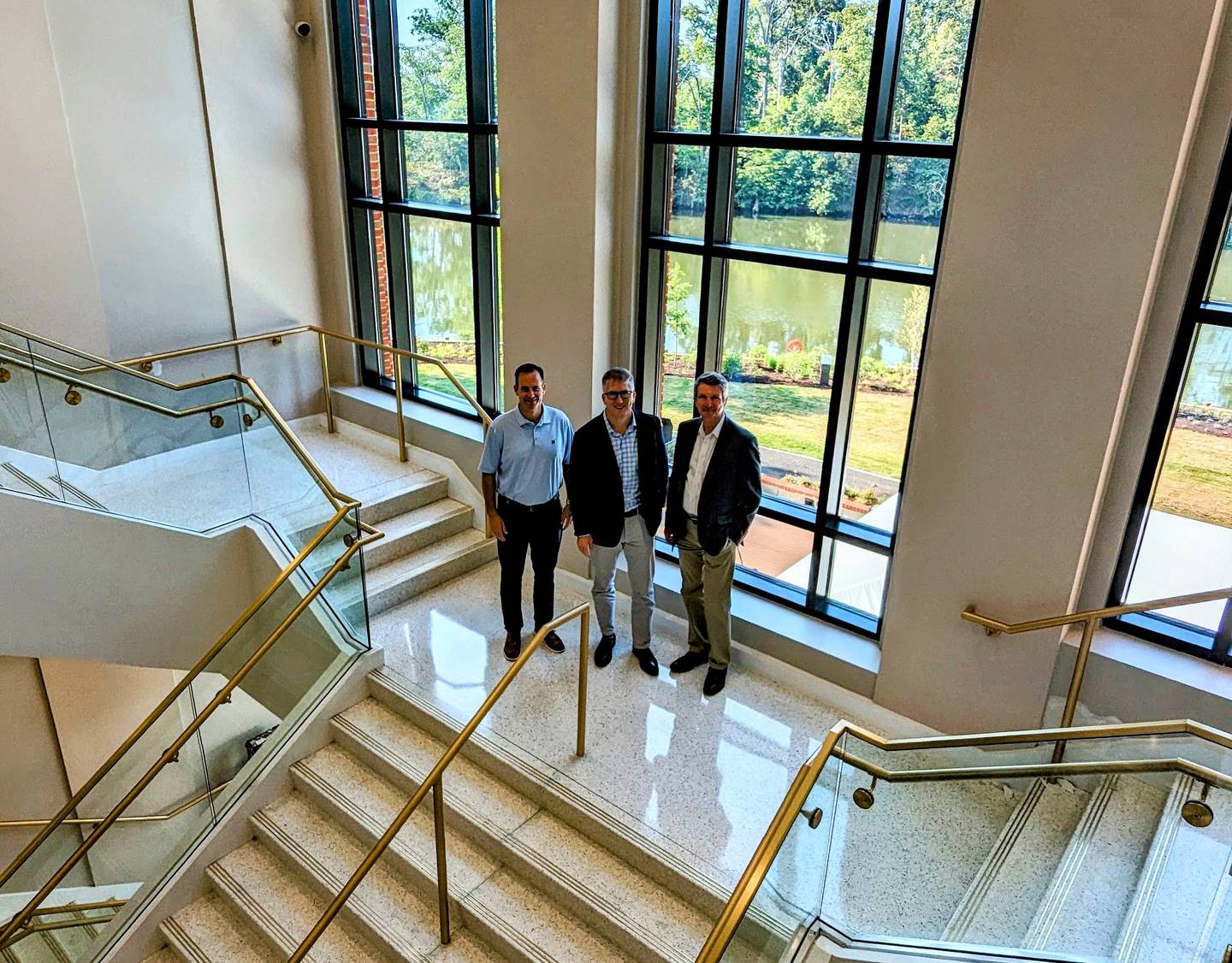 Jeff Webb, CEO of the Naval Academy Alumni Association & Foundation stands in the main stairwell of the new Fluegel Alumni Center with, left, Executive Vice Presidents Thomas Grady and, right, Bob O'Connor.