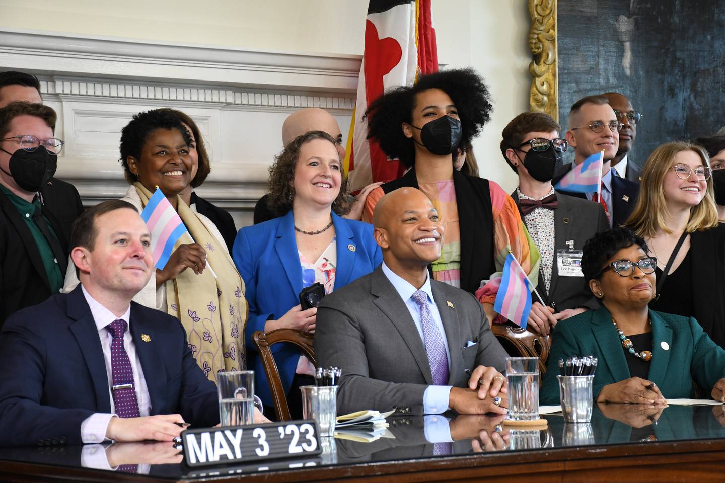 Lawmakers and advocates hold transgender pride flags and pose for pictures with Maryland Senate President Bill Ferguson, left, Gov. Wes Moore and House of Delegates Speaker Adrienne A. Jones during a ceremony at the State House in Annapolis on Wednesday, May 3, 2023. The Trans Equity Health Act was signed into law.