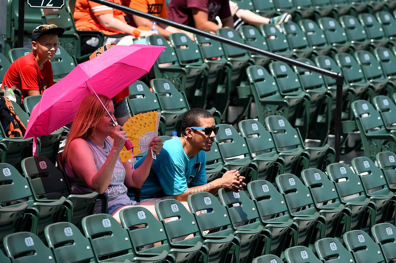 Fans try to cool off under an umbrella during the game between the Baltimore Orioles and the Boston Red Sox at Oriole Park at Camden Yards.