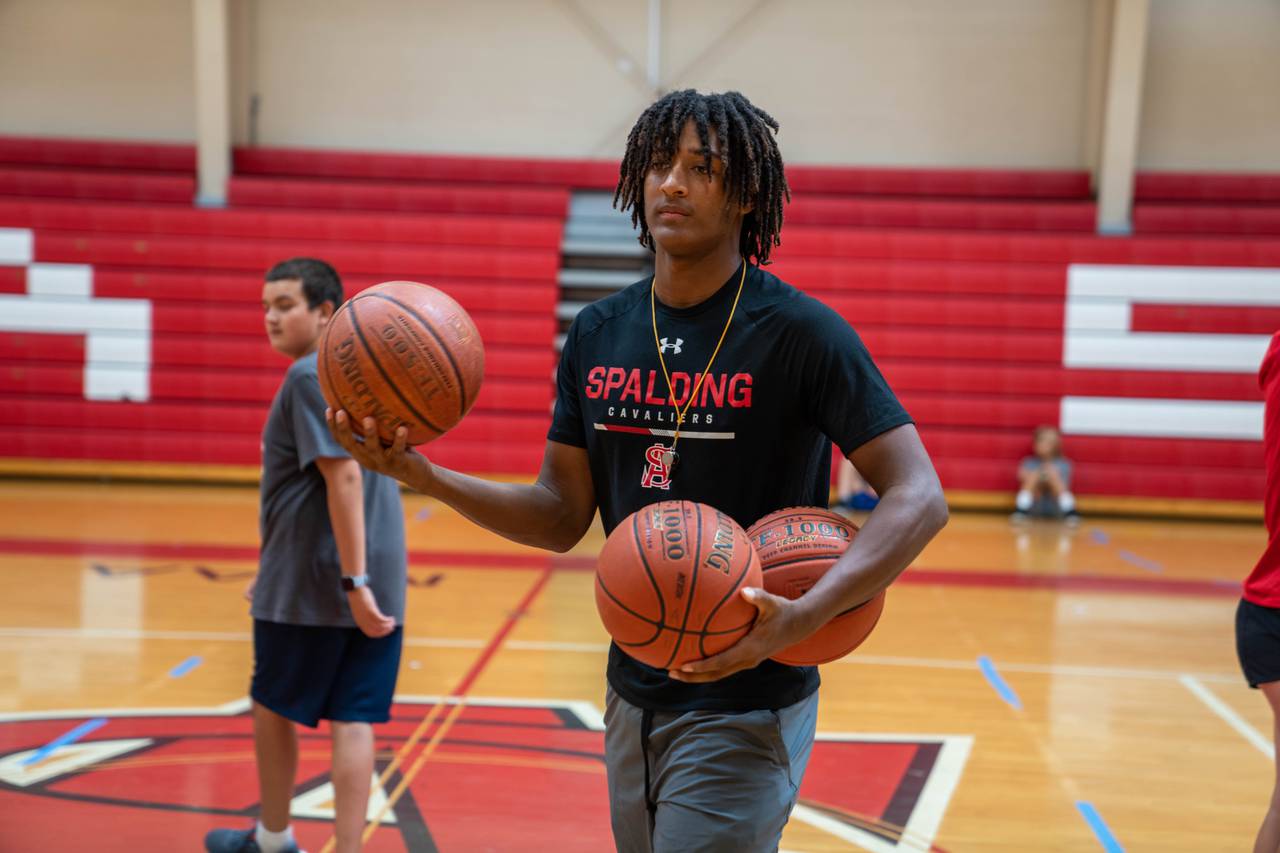 Malik Washington works with youth at a basketball camp.
