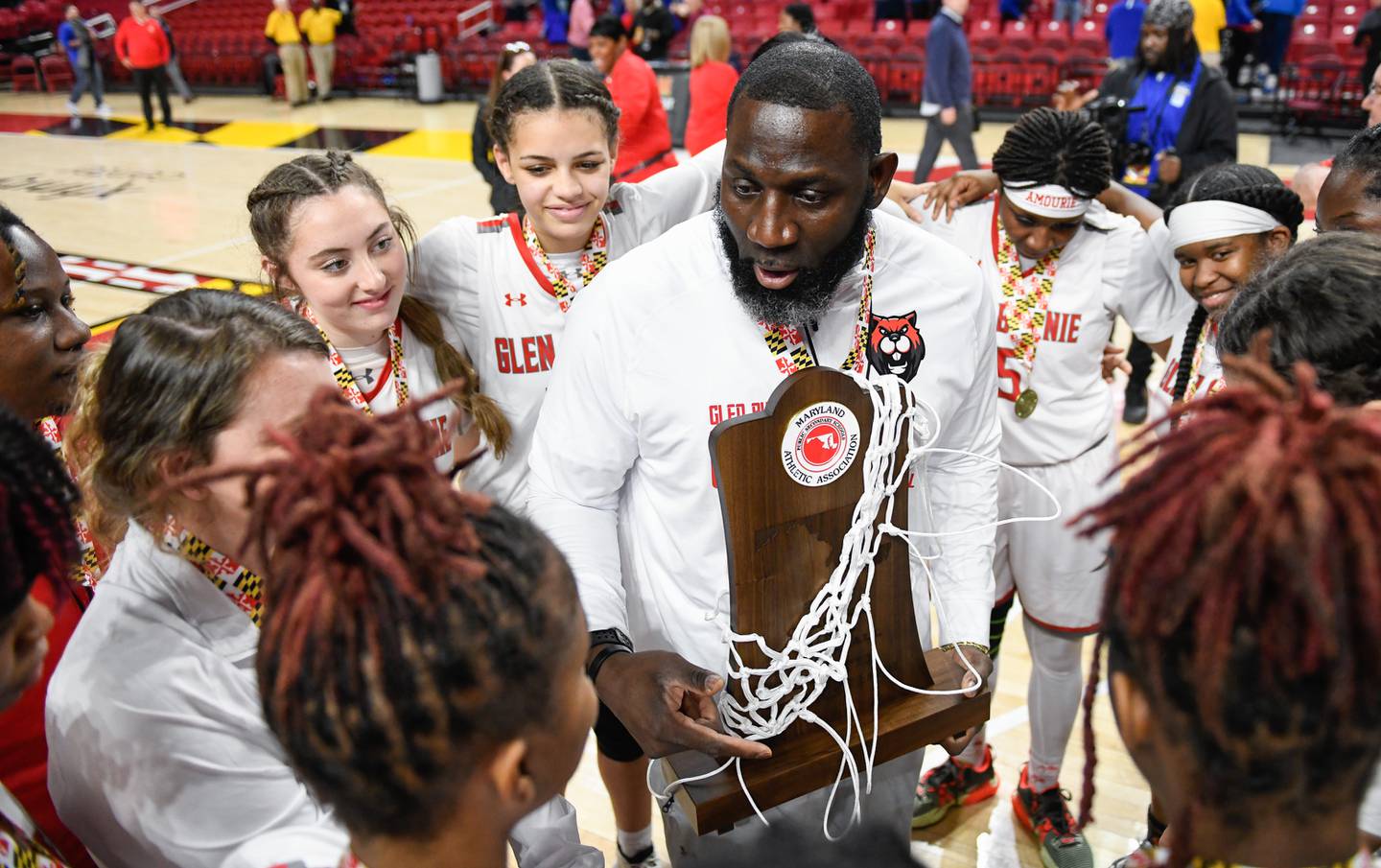 Glen Burnie head coach Sam Porter holds the Class 4A state girls basketball championship trophy as his team celebrates their 43-40 win against Churchill in College Park on Friday, March 10, 2023.