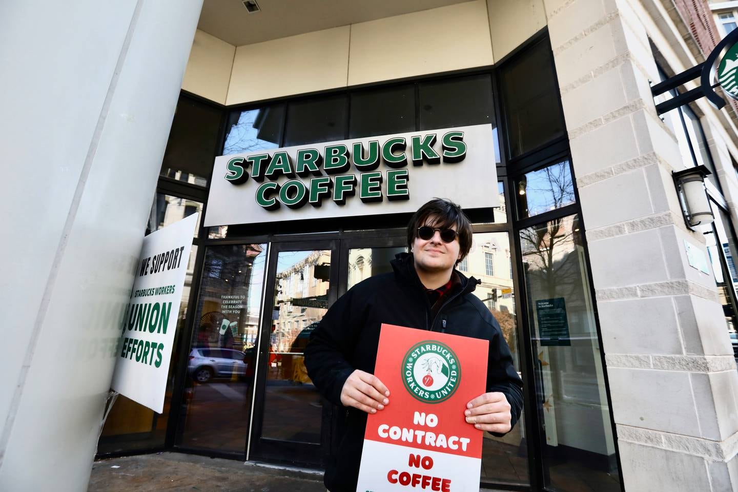 Violet bovine (she/her) and Starbucks employees cite labor issues while on strike at Baltimore’s North Charles St, location.