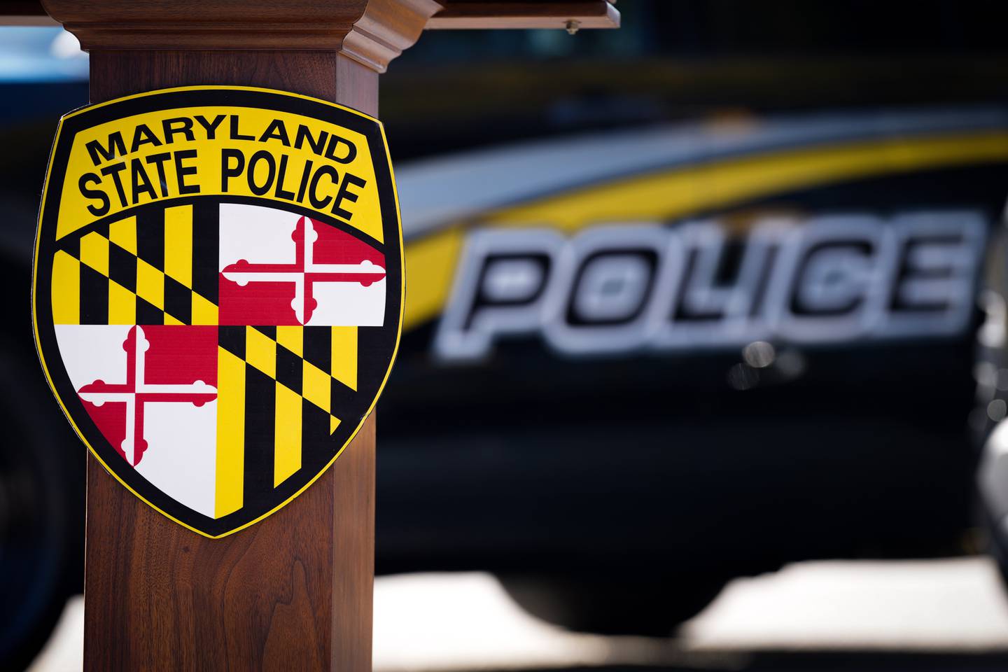 The Maryland State Police logo emblazoned on a lectern in front a police vehicle from a separate agency before a press conference, pictured outside the Maryland State Police Glen Burnie Barracks on 11/10/22.