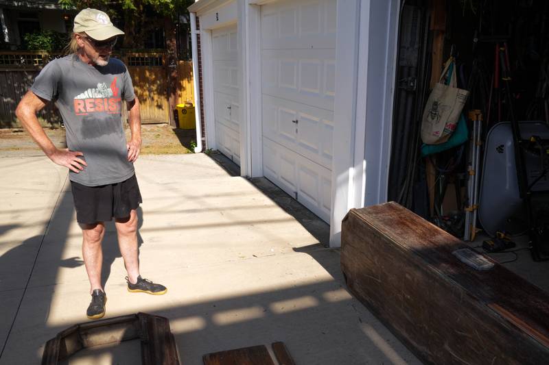 Artist Ashley Kidner examines Mathilda Lorenz’s empty casket outside his garage on July 28, 2022. The mysterious casket was originally found down by a stream in Wyman Park.