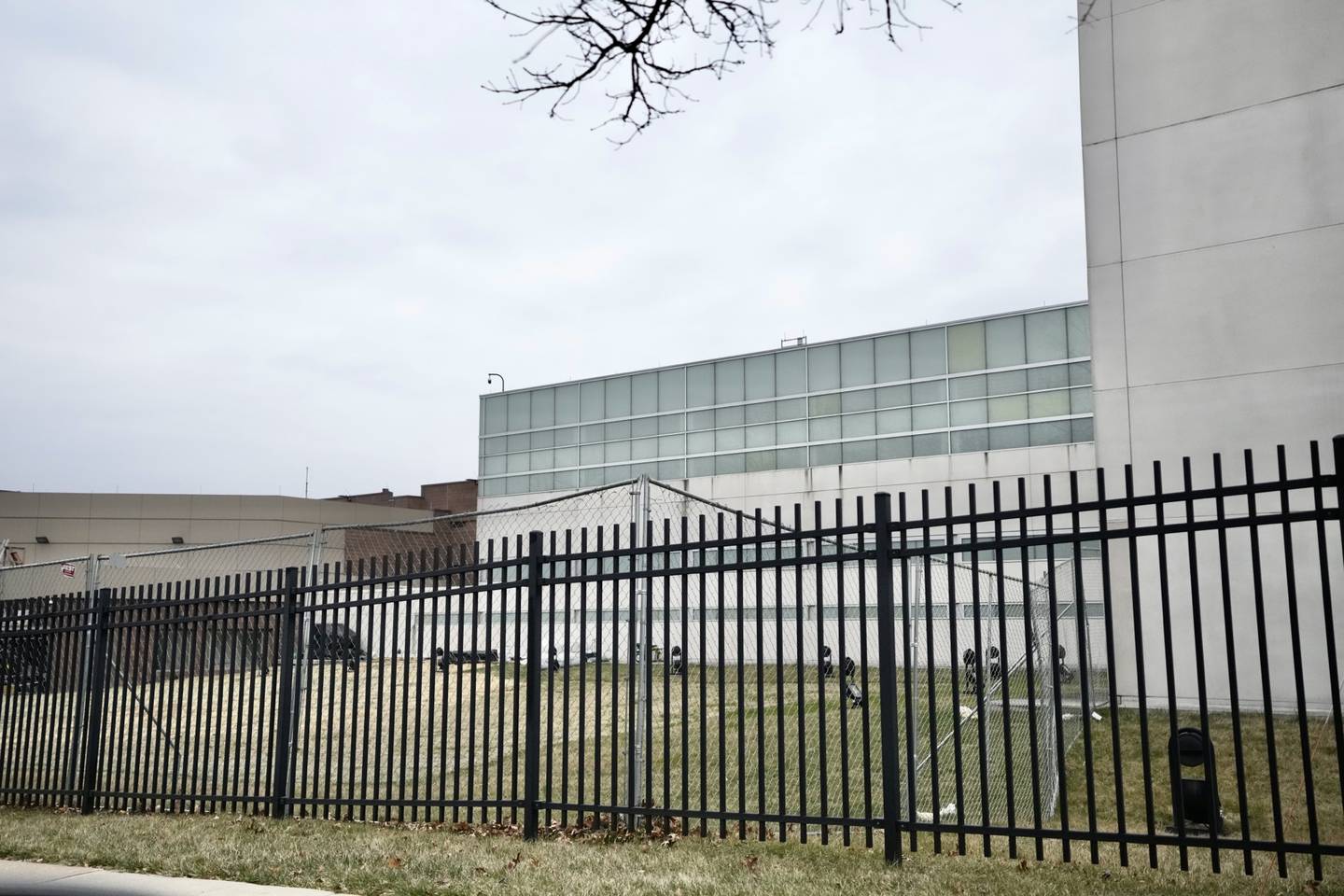 The gray exterior of the Baltimore County Detention Center can be seen behind a black metal fence.