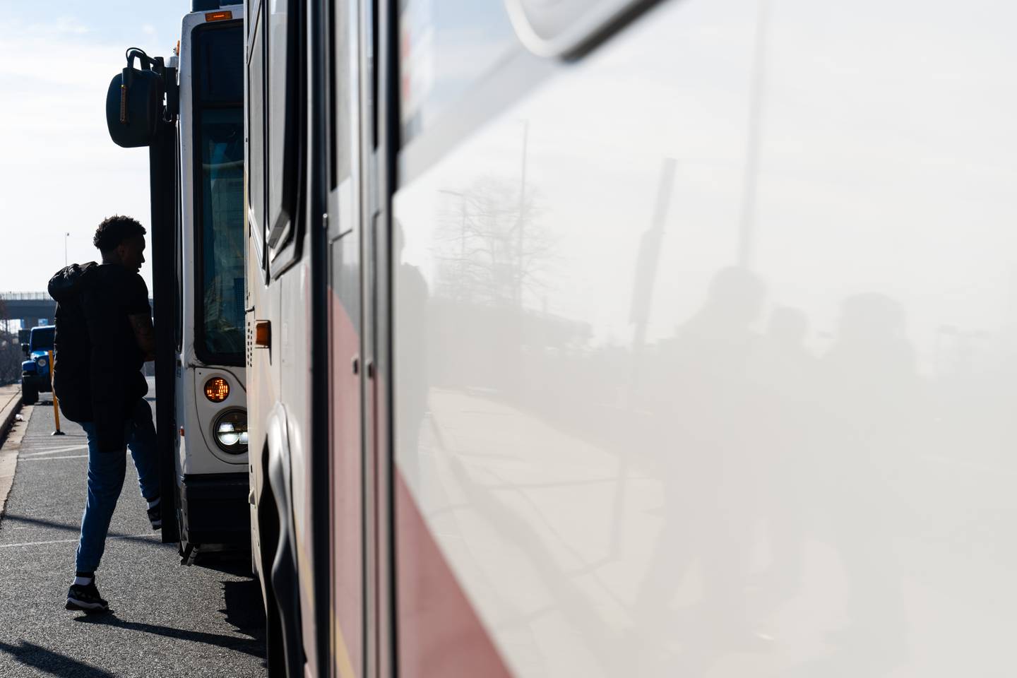 A rider, seen in silhouette, boards a shuttle bus.