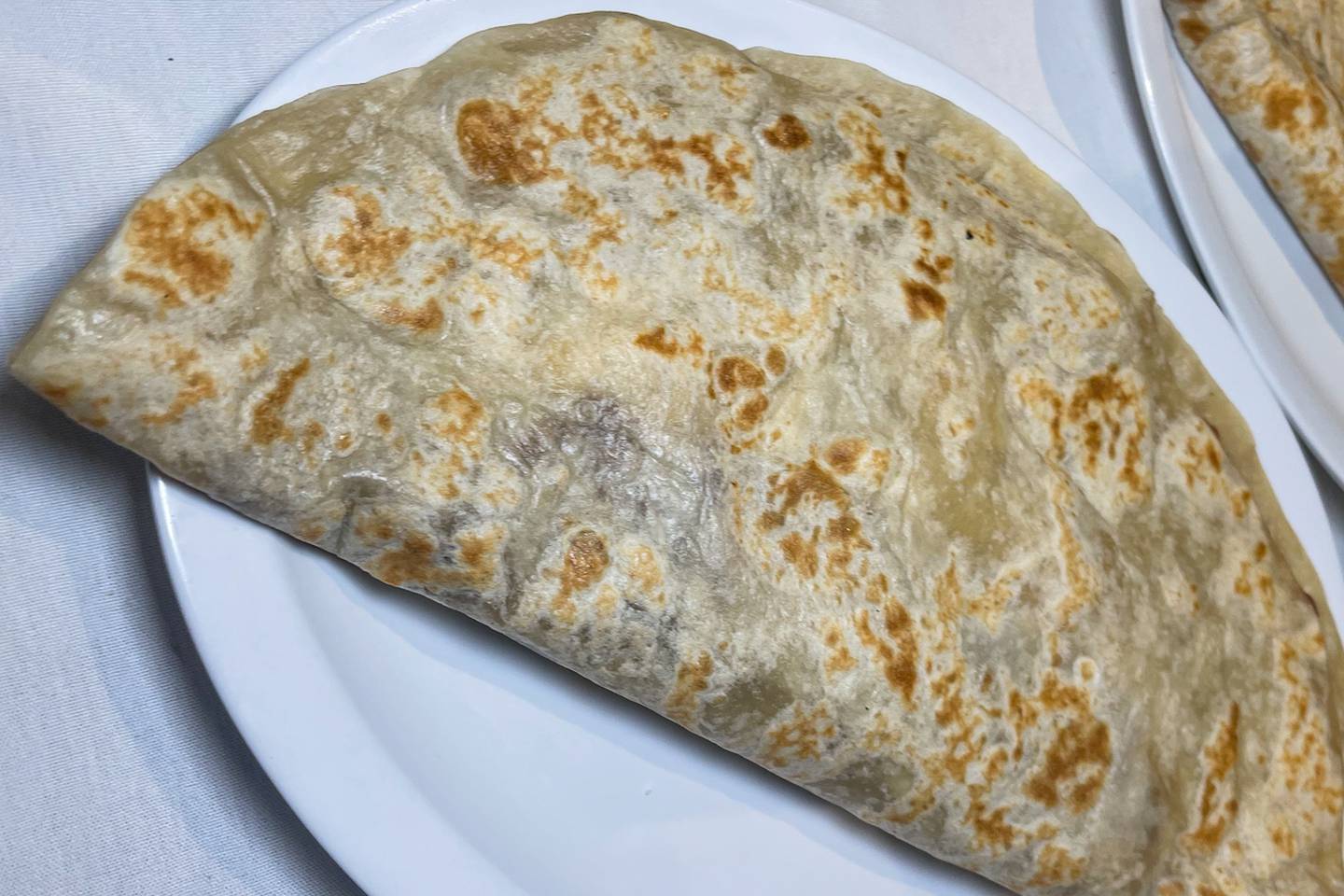 Baleadas, a traditional Honduran dish with beans, queso, crema and meat, rest on a plate