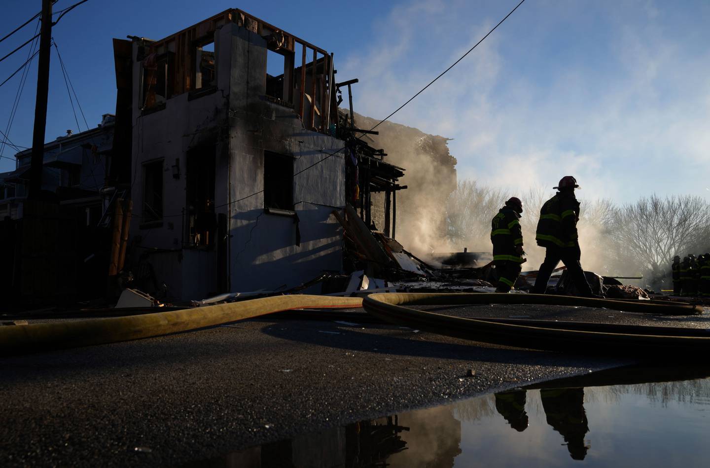 Two firefighters walk by the scene of a home that exploded in Southwest Baltimore Tuesday afternoon.