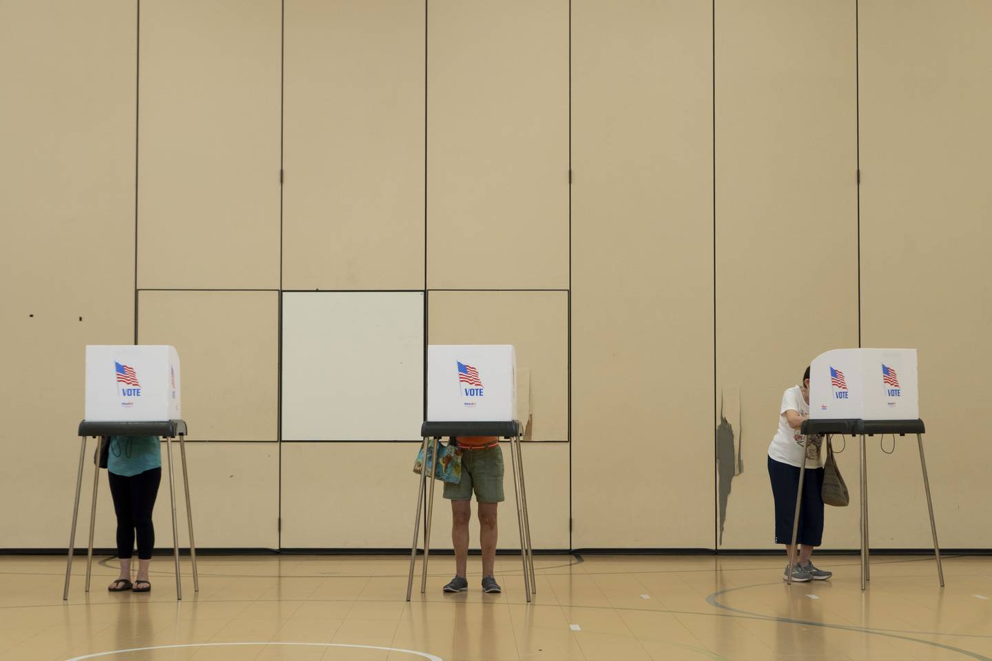 Three voters stand in their polling booths at Mays Chapel Elementary School in Baltimore County.