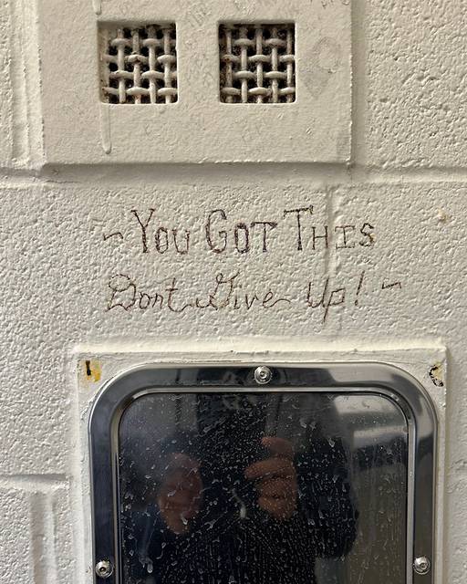 Photograph of a motivational message written onto the cinder block wall of the jail: "You got this. Don't give up!"