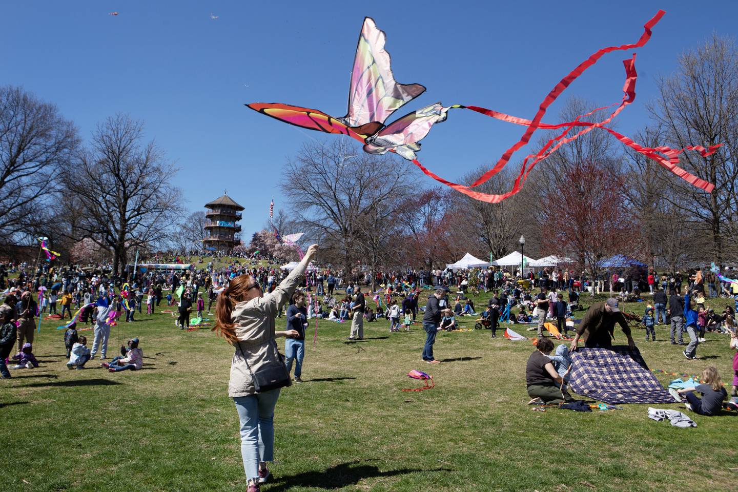 People enjoy a nice day by flying kites at Patterson Park during the Kite Festival on March 26, 2023. (Julia Reihs for The Baltimore Banner)