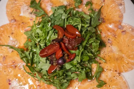 Salmon Carpaccio salad with arugula and tomatoes.