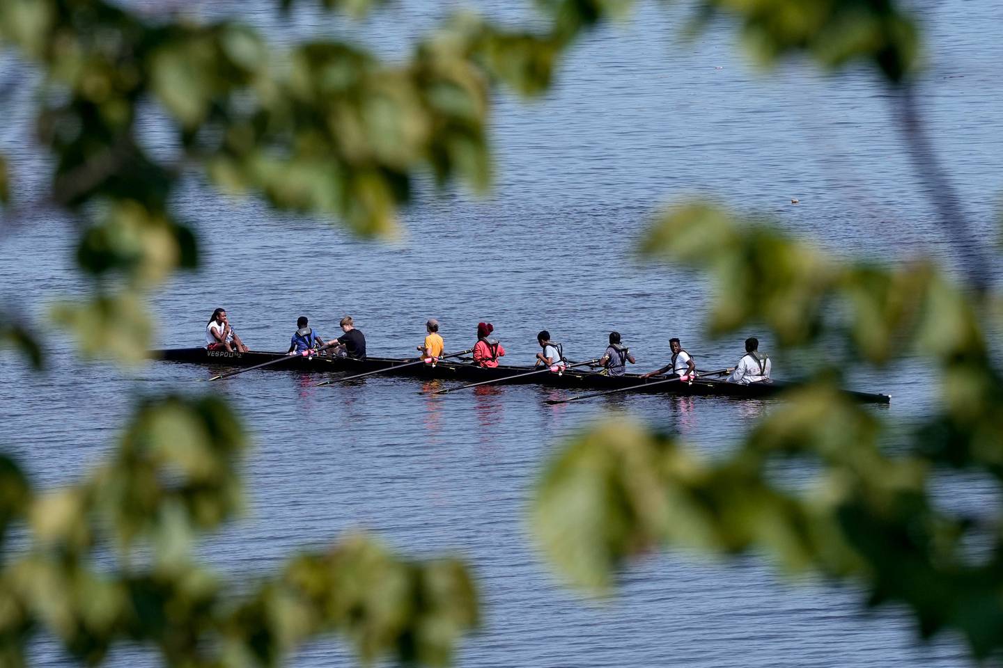 Kids from Restoring Inner Cities Hope paddle through the water on an 8 person boat with BCR instructors on Aug. 2, 2023.