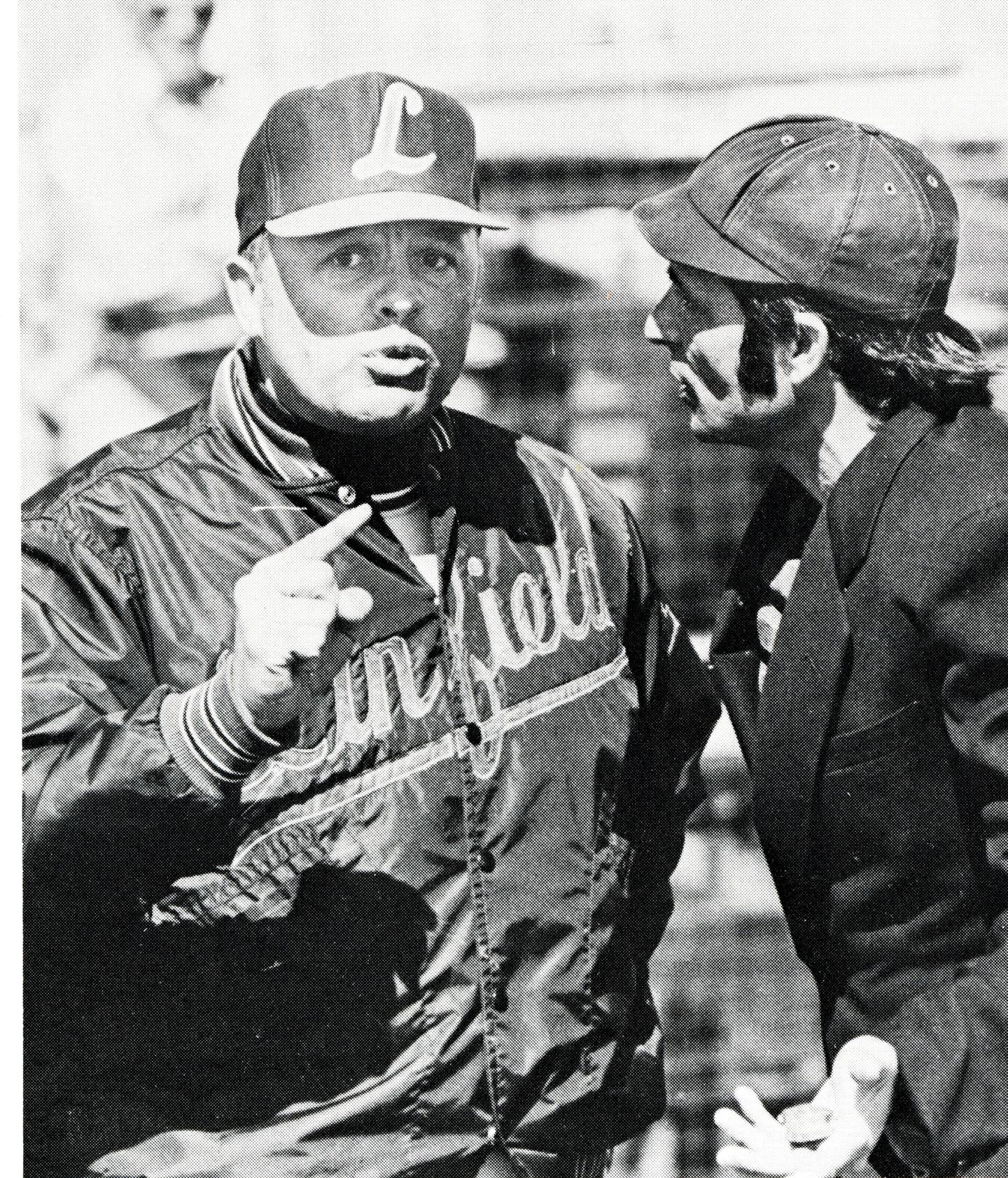 Ad Rutschman, who coached baseball and football for years at Linfield University in Oregon, speaks with an umpire.