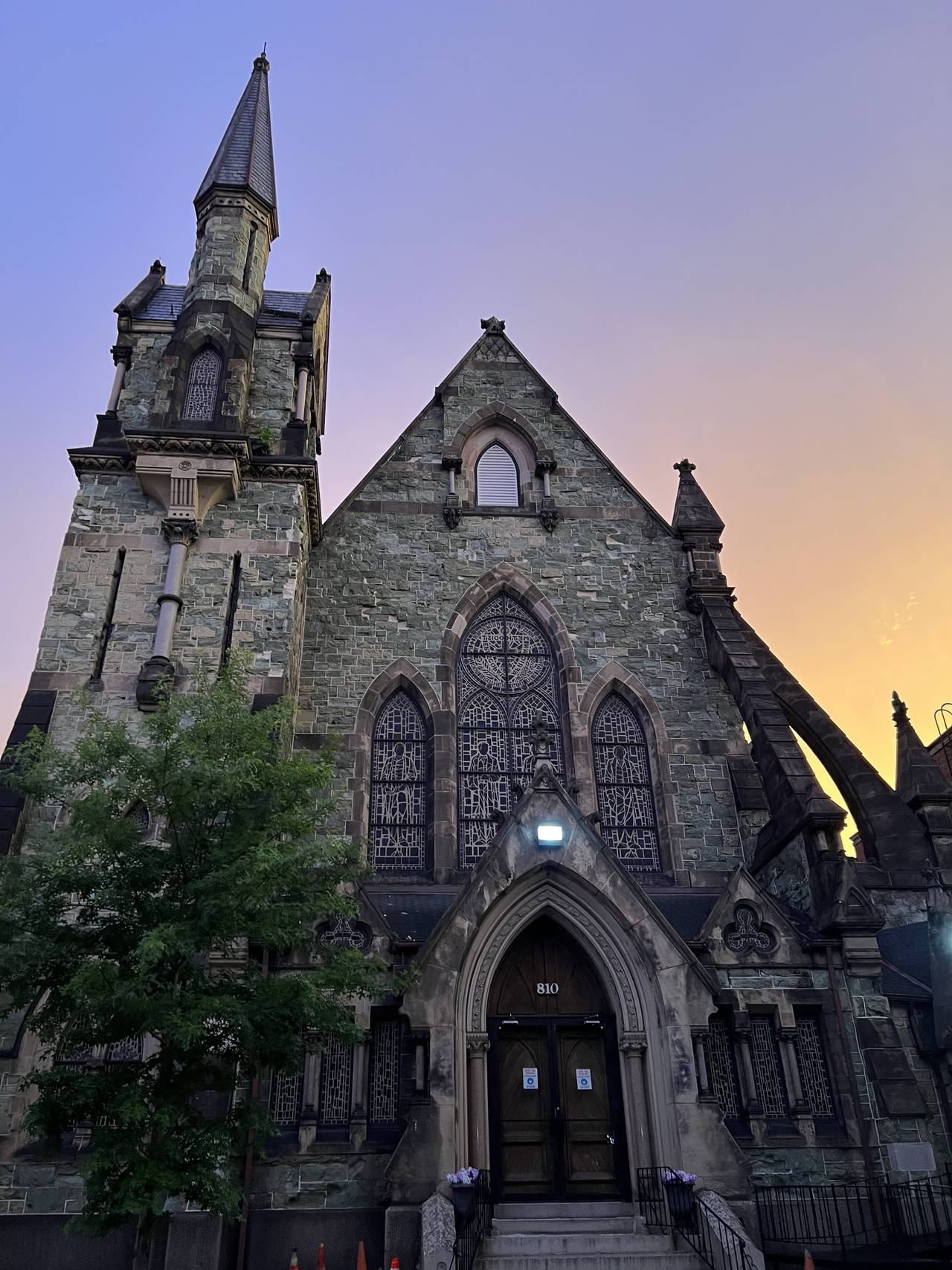 An old stone church sits against a purple and orange sky.