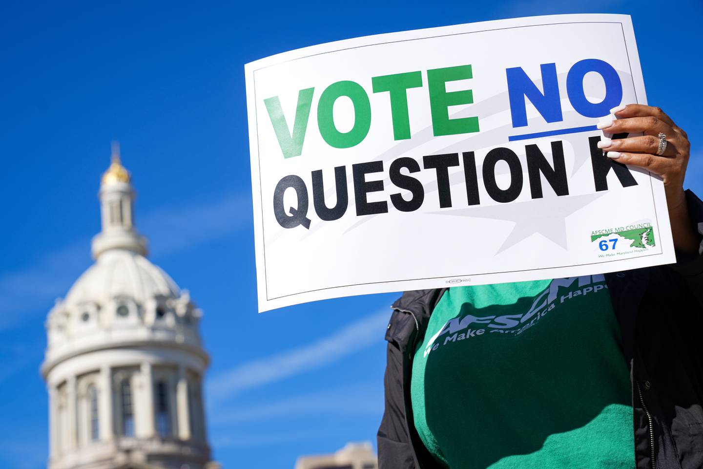 A member of AFSCME Council 67 holds up a sign encouraging Baltimore voters to vote no on Question K in the upcoming general election during a press conference at War Memorial Plaza on 10/6/22. The question would determine whether or not term limits are imposed on a number of elected positions in the city. (Ulysses Muñoz/The Baltimore Banner)