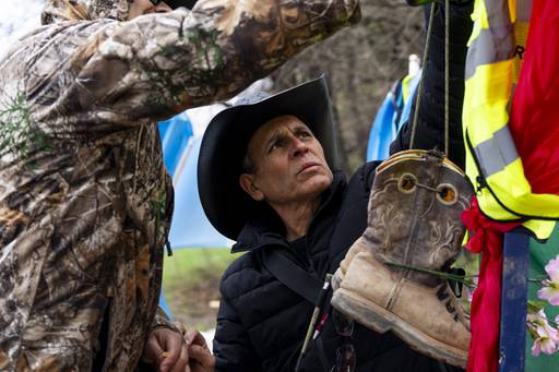 Roberto Marquez, an artist from Dallas, TX, hangs boots on several crosses bearing the victims names on April 6, 2024.